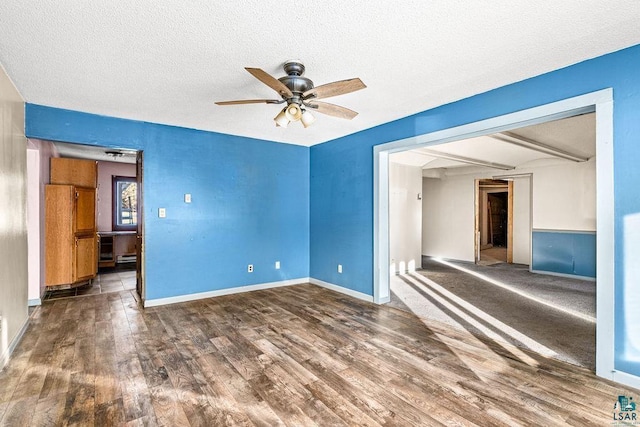 unfurnished room featuring beamed ceiling, a textured ceiling, dark hardwood / wood-style floors, and ceiling fan