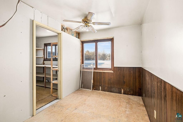 unfurnished room featuring ceiling fan and wooden walls