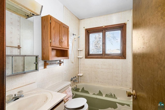 full bathroom with vanity, tiled shower / bath combo, toilet, and tile walls