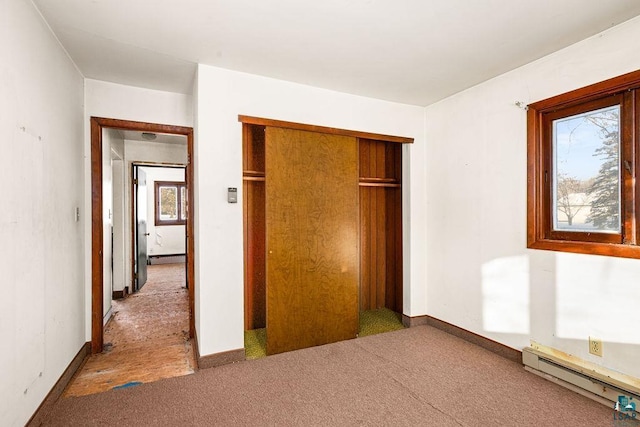 unfurnished bedroom featuring carpet, a closet, and a baseboard heating unit