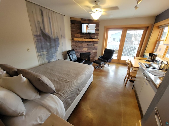 bedroom with access to outside, a stone fireplace, and ceiling fan