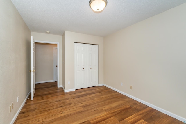 unfurnished bedroom with a closet, wood-type flooring, and a textured ceiling