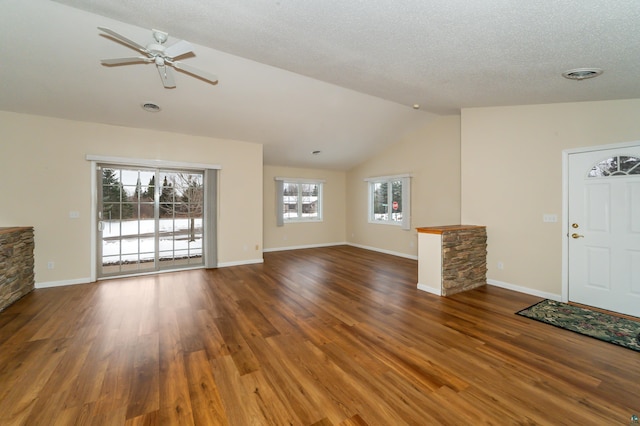 unfurnished living room with lofted ceiling, a stone fireplace, ceiling fan, a textured ceiling, and dark hardwood / wood-style flooring