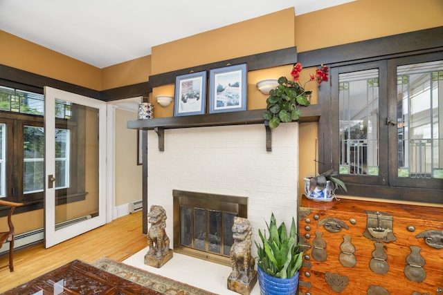 living room with wood-type flooring, a fireplace, and a baseboard heating unit