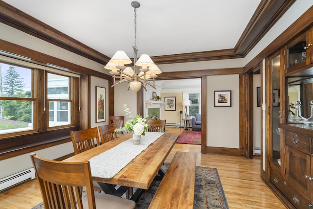 dining space featuring a chandelier, light wood-type flooring, baseboard heating, and crown molding