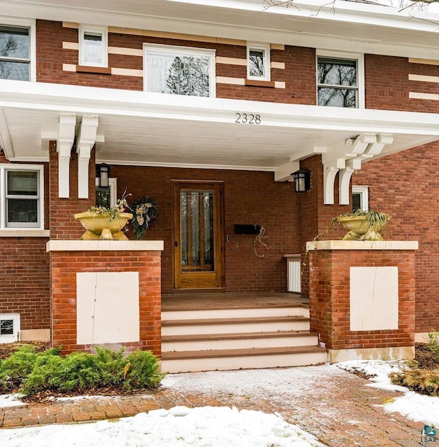 snow covered property entrance with covered porch