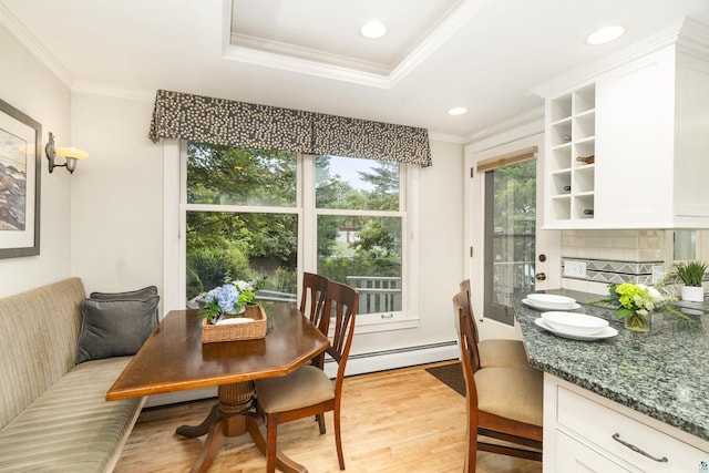 dining space featuring a raised ceiling, ornamental molding, a baseboard radiator, and light wood-type flooring