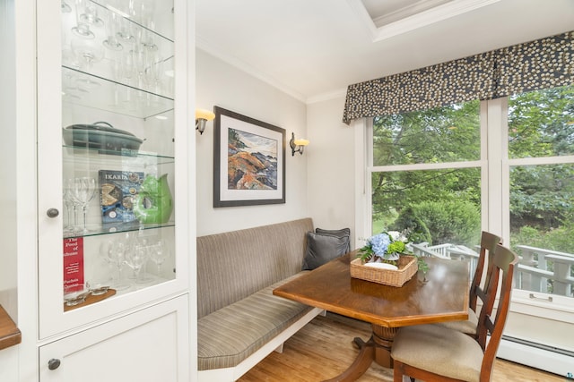 dining room featuring breakfast area, a baseboard radiator, light hardwood / wood-style flooring, and a healthy amount of sunlight