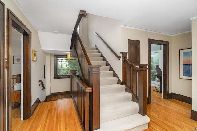 stairway with hardwood / wood-style flooring and crown molding