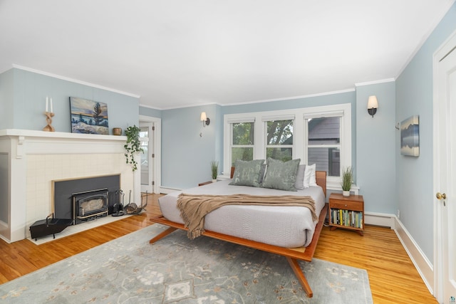 bedroom with hardwood / wood-style floors, ornamental molding, and a baseboard heating unit