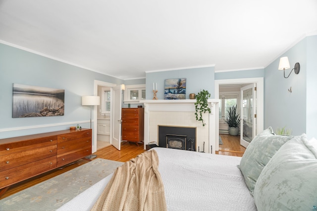 bedroom featuring light hardwood / wood-style floors, ensuite bath, and ornamental molding