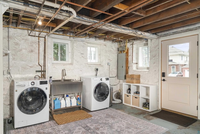 clothes washing area with electric panel, a wealth of natural light, sink, and washing machine and dryer