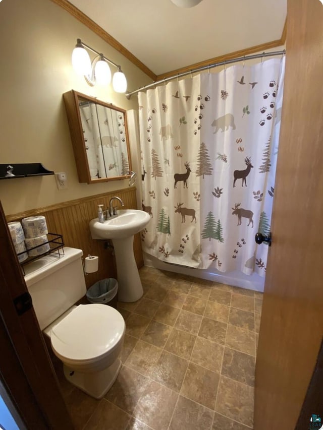 bathroom with shower / tub combo, toilet, ornamental molding, and wood walls