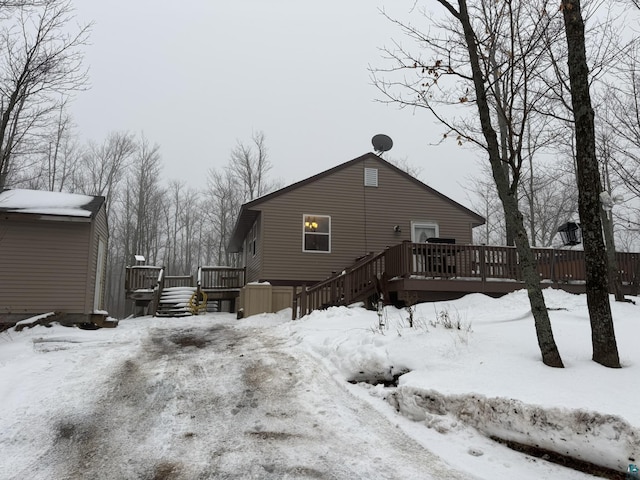 snow covered rear of property with a wooden deck