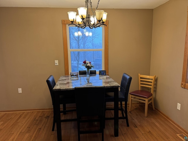 dining area with hardwood / wood-style floors and an inviting chandelier