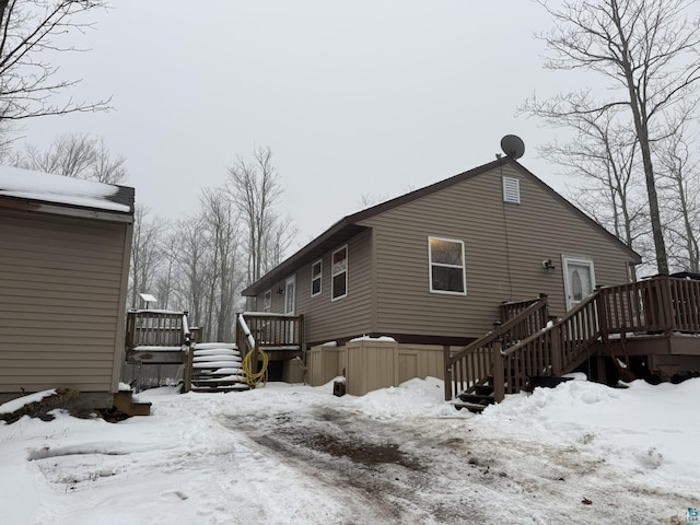 snow covered rear of property featuring a deck