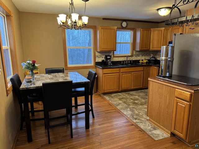 kitchen with backsplash, sink, pendant lighting, wood-type flooring, and a chandelier