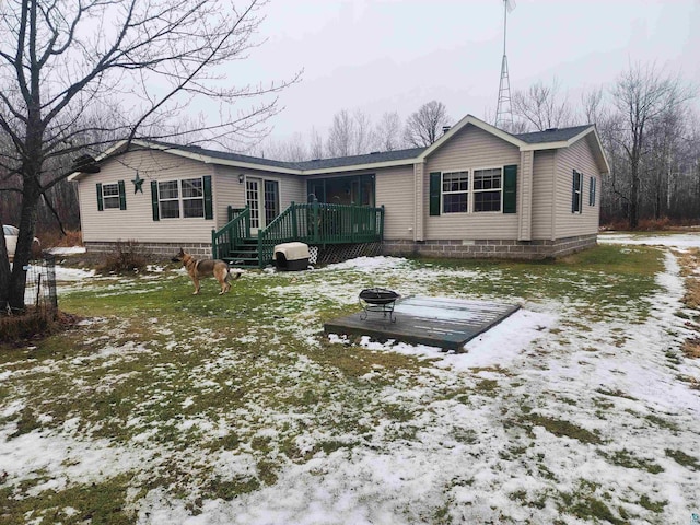 snow covered back of property featuring a fire pit and a wooden deck