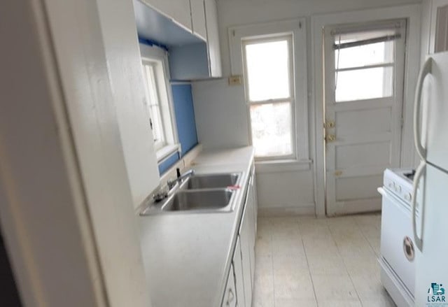 kitchen with white cabinetry, sink, plenty of natural light, and white appliances