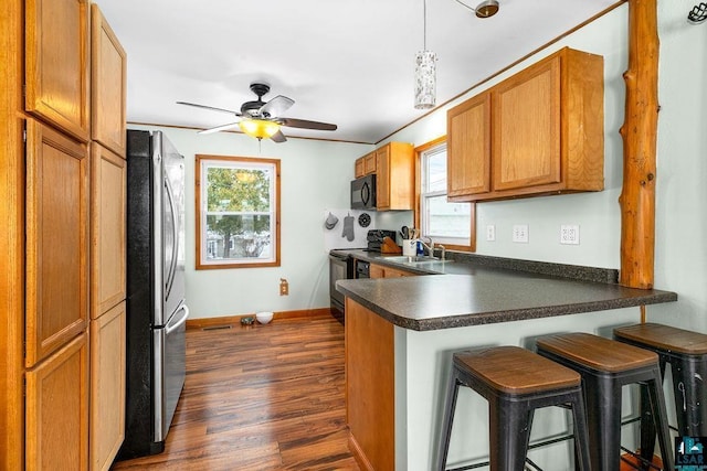 kitchen featuring sink, dark hardwood / wood-style floors, decorative light fixtures, a kitchen bar, and black appliances