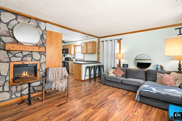 living room featuring a textured ceiling, a fireplace, wood-type flooring, and crown molding