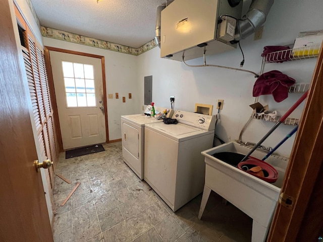 washroom featuring sink, washing machine and dryer, a textured ceiling, and electric panel