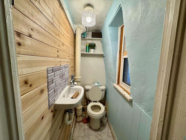 bathroom with wood walls, toilet, and sink