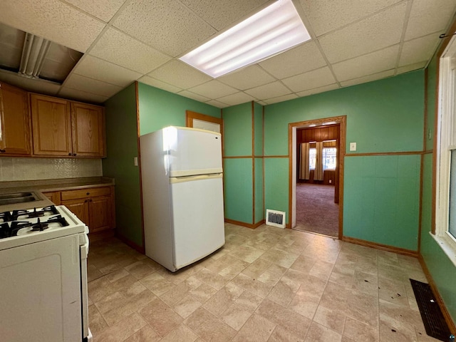 kitchen with a paneled ceiling and white appliances