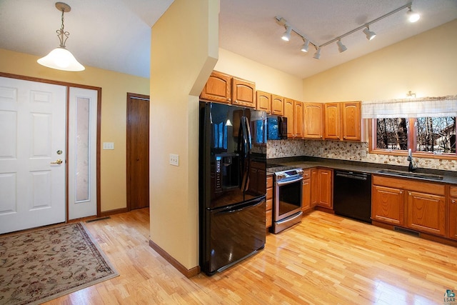 kitchen featuring sink, hanging light fixtures, light hardwood / wood-style floors, decorative backsplash, and black appliances