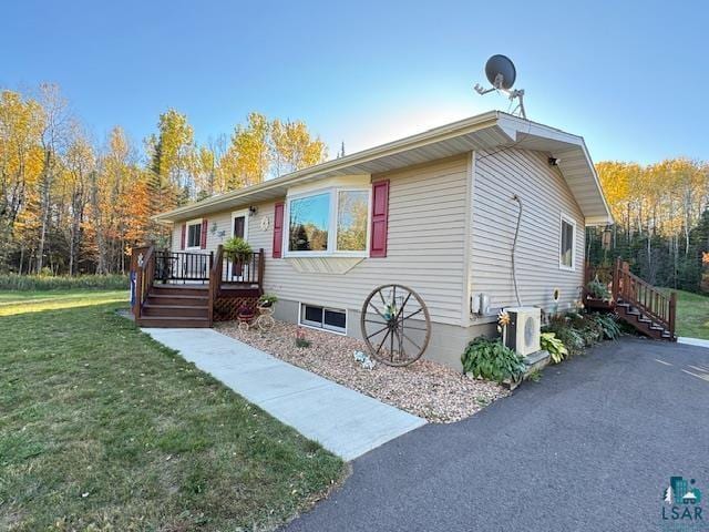 view of front facade featuring ac unit, a wooden deck, and a front lawn