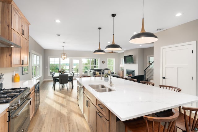 kitchen with a breakfast bar area, a large island with sink, sink, and stainless steel appliances