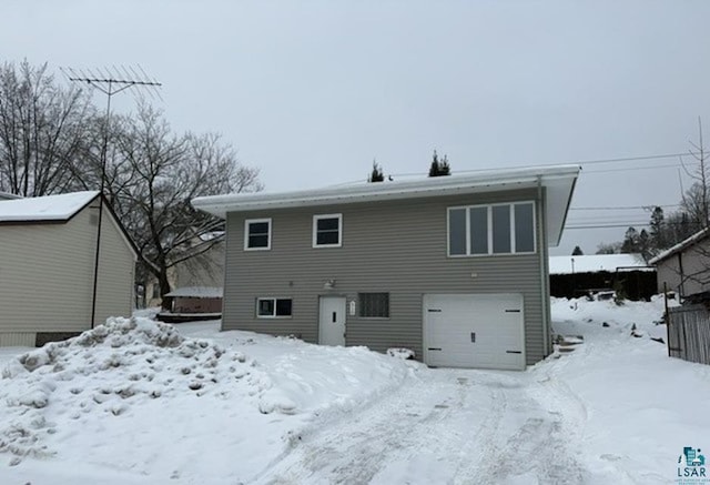 snow covered rear of property with a garage