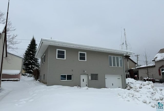 snow covered property with a garage