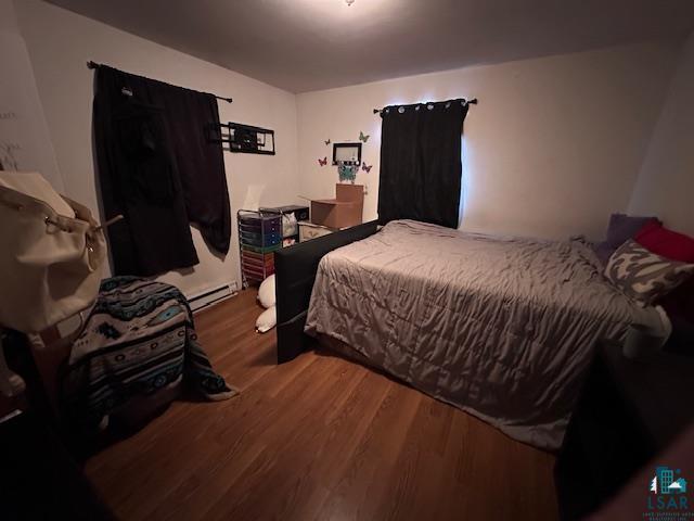 bedroom featuring baseboard heating and dark hardwood / wood-style floors