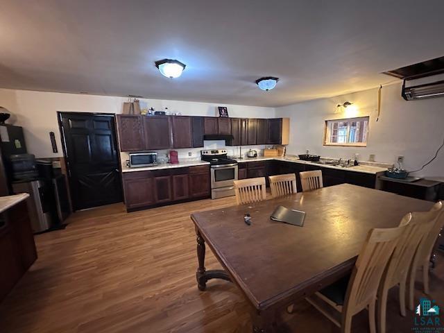 kitchen with dark brown cabinets, stainless steel appliances, and light hardwood / wood-style flooring