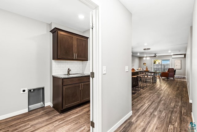 bar featuring a wall mounted air conditioner, tasteful backsplash, dark brown cabinets, ceiling fan, and dark hardwood / wood-style floors