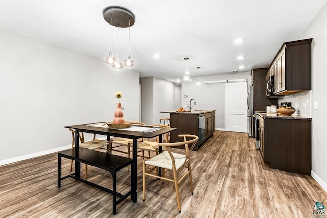 dining room with hardwood / wood-style flooring, a barn door, and sink