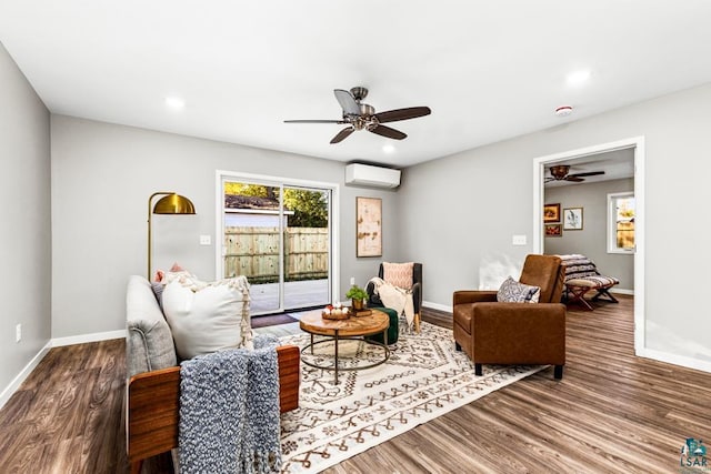 living room featuring wood-type flooring, a wall unit AC, and ceiling fan