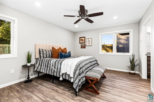 bedroom with hardwood / wood-style floors, ceiling fan, and multiple windows