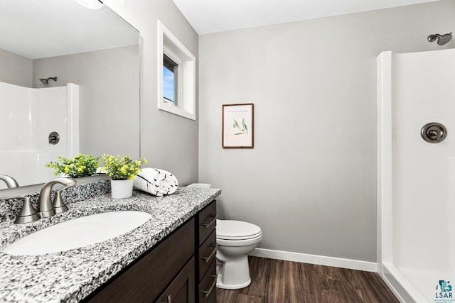 bathroom featuring a shower, hardwood / wood-style floors, vanity, and toilet