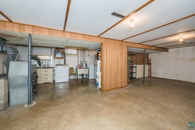 basement featuring wood walls, sink, and washing machine and clothes dryer