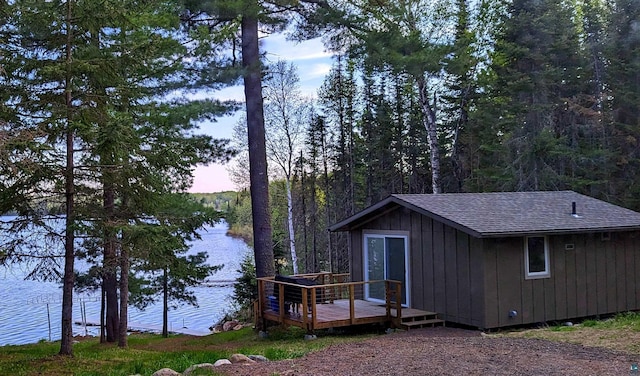 property exterior at dusk featuring a deck with water view and an outdoor structure