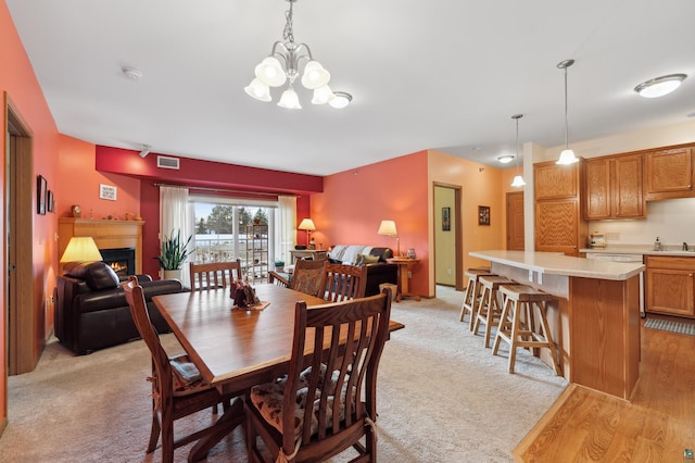 dining space featuring light carpet and an inviting chandelier