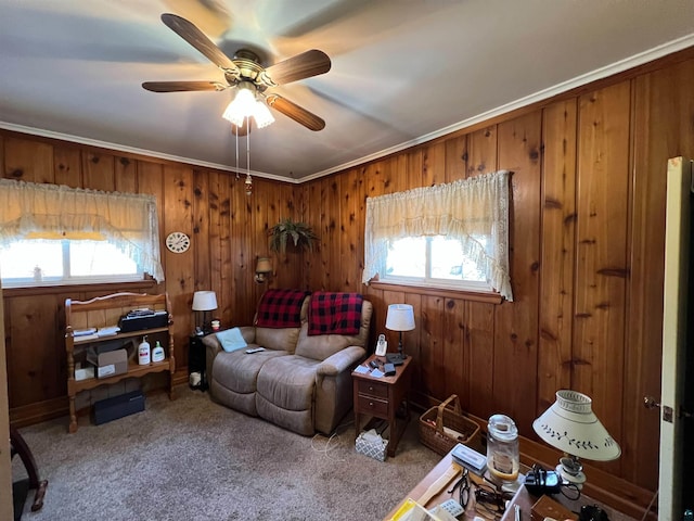 living room with carpet flooring, ceiling fan, wood walls, and ornamental molding