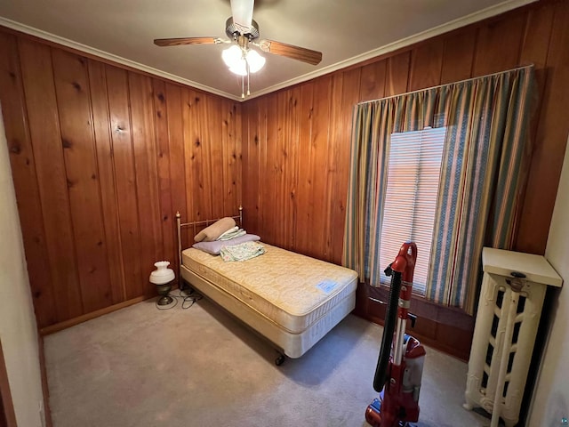 carpeted bedroom featuring ceiling fan, ornamental molding, and wood walls