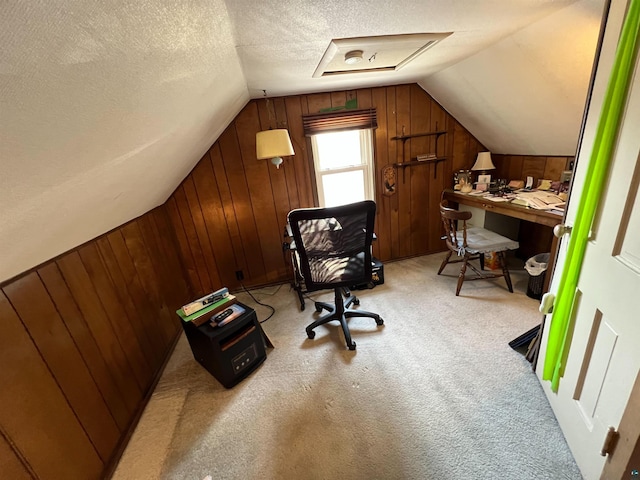 home office with vaulted ceiling, wood walls, light colored carpet, and a textured ceiling