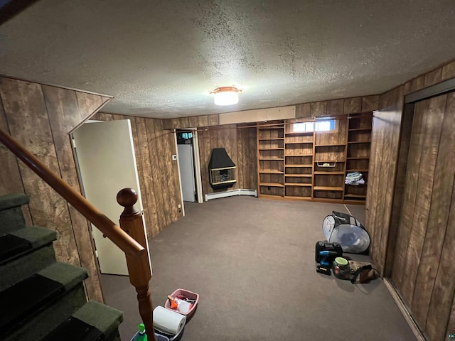 basement with wooden walls, carpet floors, a baseboard radiator, and a textured ceiling