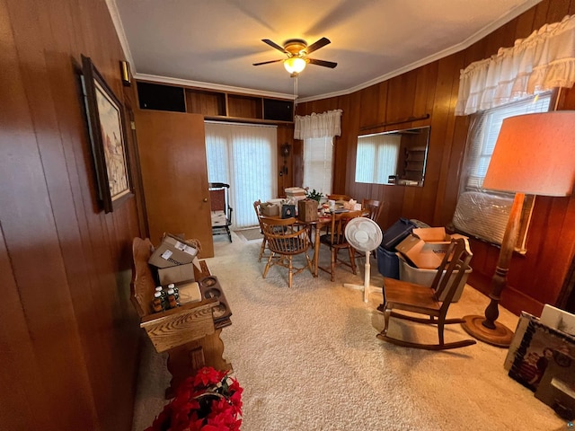 sitting room with carpet flooring, ceiling fan, ornamental molding, and wooden walls