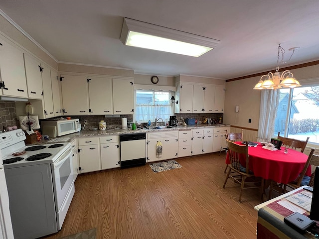 kitchen with white appliances, decorative light fixtures, a notable chandelier, white cabinets, and light hardwood / wood-style floors