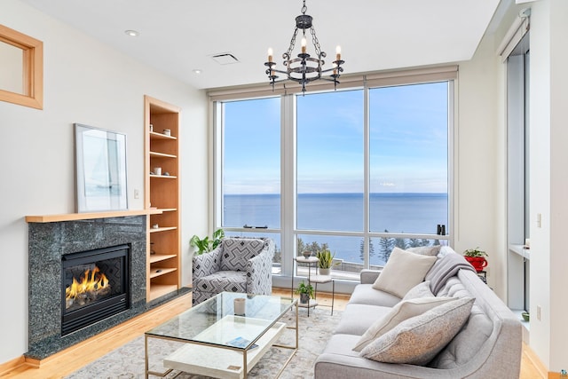 living room featuring a notable chandelier, plenty of natural light, a water view, and a high end fireplace